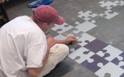 Maler streicht einen Fussboden mit einem Puzzelstück - Muster 